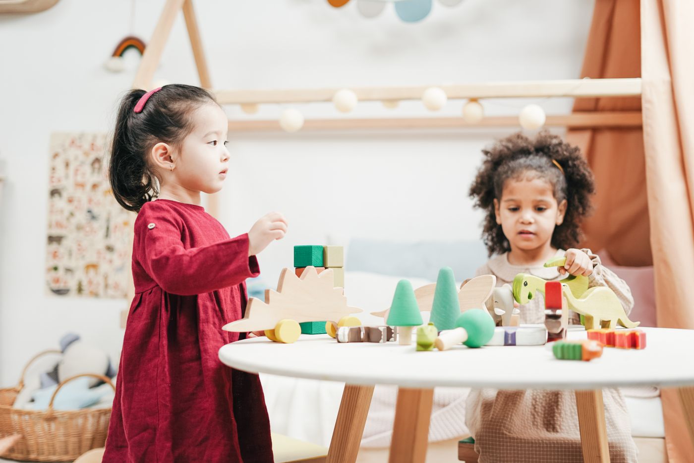 Zwei Kinder spielen gemeinsam mit bunten Holzfiguren in einem hellen Spielzimmer
